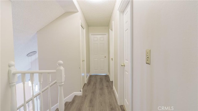 hallway featuring light hardwood / wood-style floors and a textured ceiling