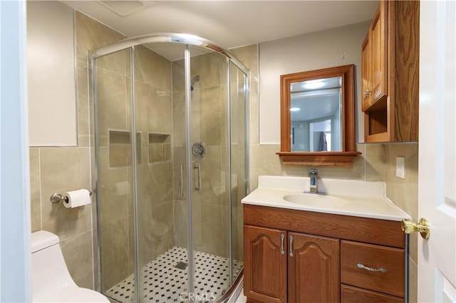 bathroom with vanity, toilet, a shower with shower door, and backsplash