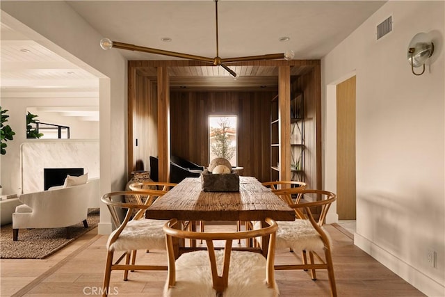 dining room featuring hardwood / wood-style floors, wood walls, and a fireplace