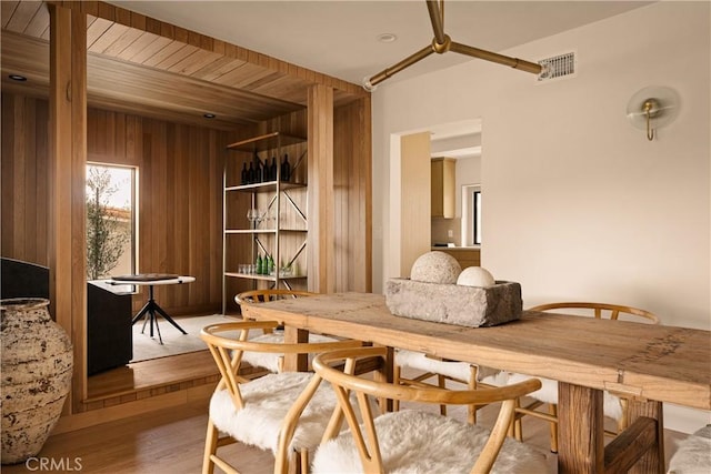 dining area with wood walls and light hardwood / wood-style flooring