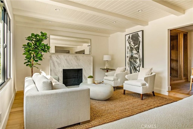 living room with a fireplace, beamed ceiling, and wood-type flooring