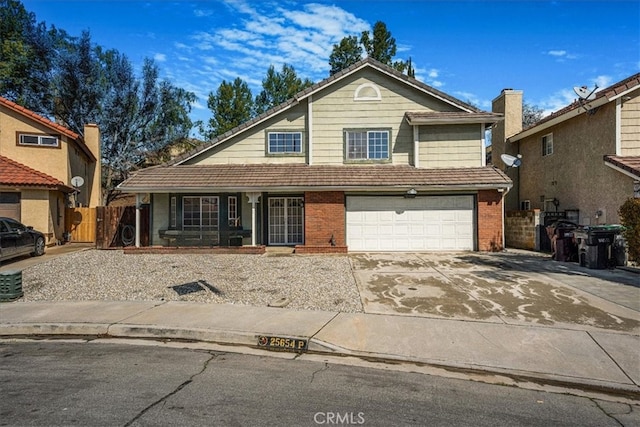 view of front of house featuring brick siding, an attached garage, driveway, and fence