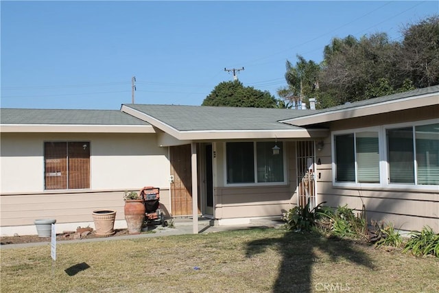 view of front of property featuring roof with shingles and a front lawn