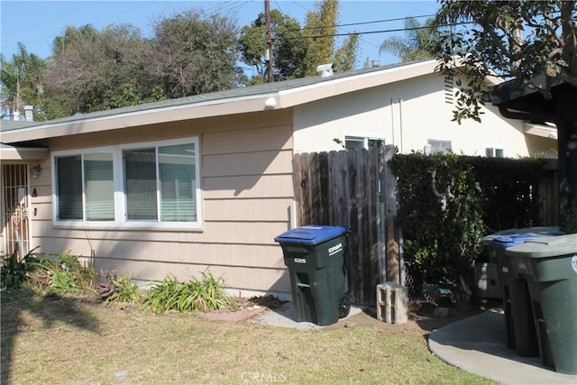 view of side of home with a lawn and fence