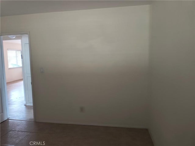 empty room with stone tile floors and baseboards