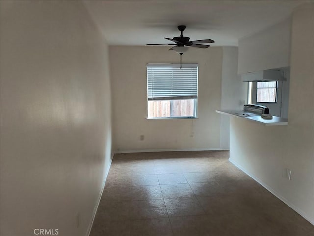 spare room featuring plenty of natural light, baseboards, and ceiling fan