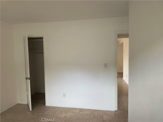 spare room featuring tile patterned floors and baseboards