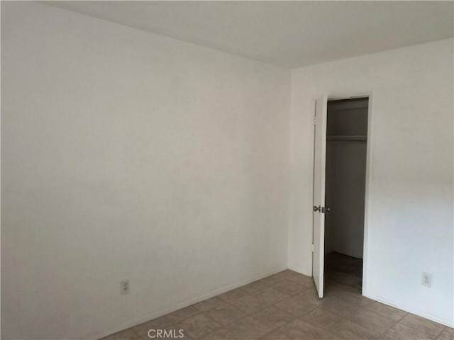 unfurnished bedroom featuring a closet, light floors, a spacious closet, and baseboards