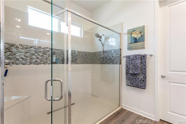 bathroom with wood-type flooring and a shower with shower door