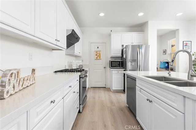 kitchen featuring custom exhaust hood, sink, light hardwood / wood-style floors, white cabinetry, and stainless steel appliances