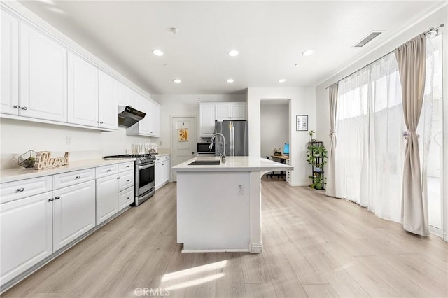 kitchen featuring light wood-type flooring, stainless steel appliances, sink, a center island with sink, and white cabinetry