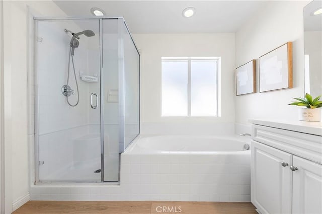 bathroom featuring hardwood / wood-style floors, vanity, and plus walk in shower