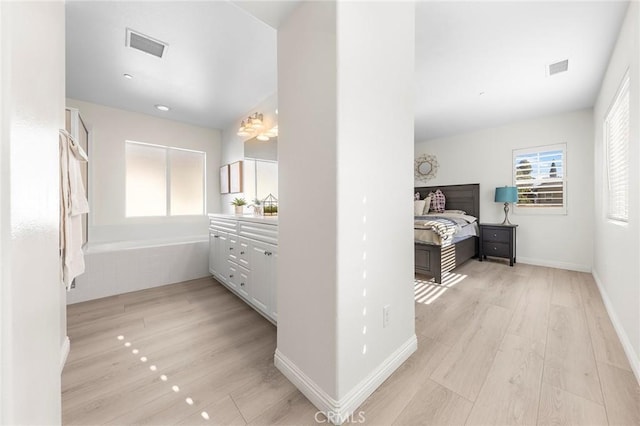 interior space with wood-type flooring, vanity, and a tub to relax in