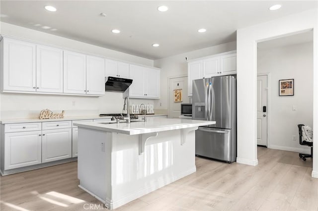 kitchen featuring white cabinets, stainless steel refrigerator with ice dispenser, a center island with sink, and built in microwave