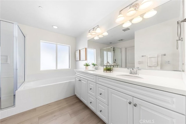 bathroom with hardwood / wood-style flooring, vanity, and shower with separate bathtub