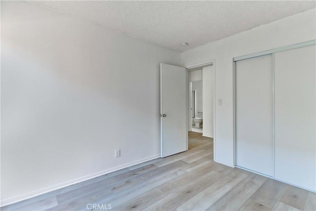 unfurnished bedroom with light hardwood / wood-style floors, a textured ceiling, and a closet