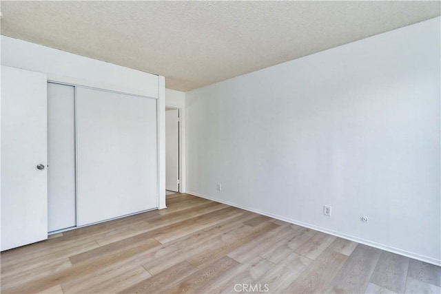 unfurnished bedroom with light wood-type flooring and a closet