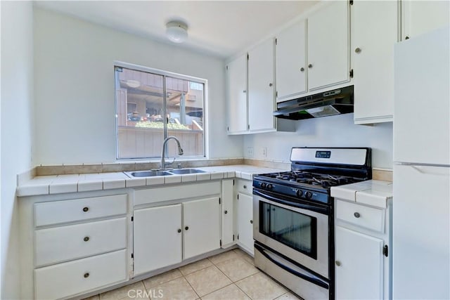 kitchen with tile countertops, white cabinets, white refrigerator, sink, and stainless steel range with gas stovetop