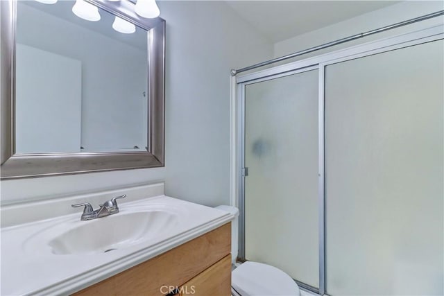 bathroom featuring vanity, toilet, and a shower with door