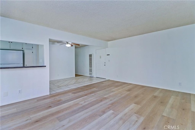 unfurnished living room featuring a textured ceiling, light hardwood / wood-style flooring, and ceiling fan