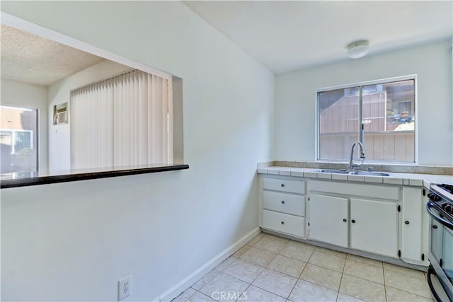 kitchen with tile countertops, a healthy amount of sunlight, range, and sink