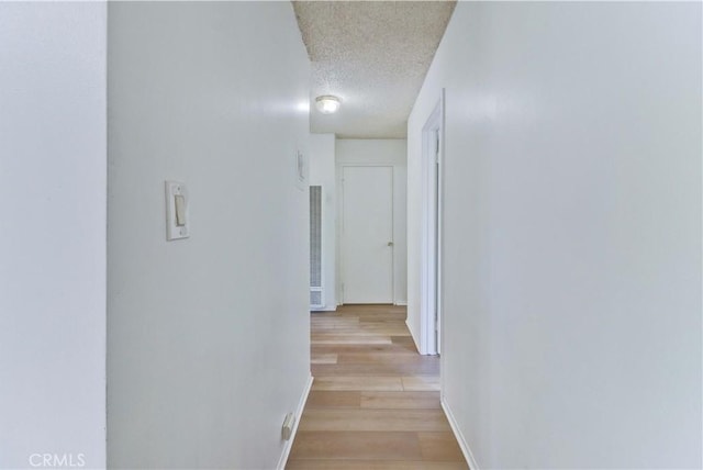 hallway featuring a textured ceiling and light hardwood / wood-style flooring