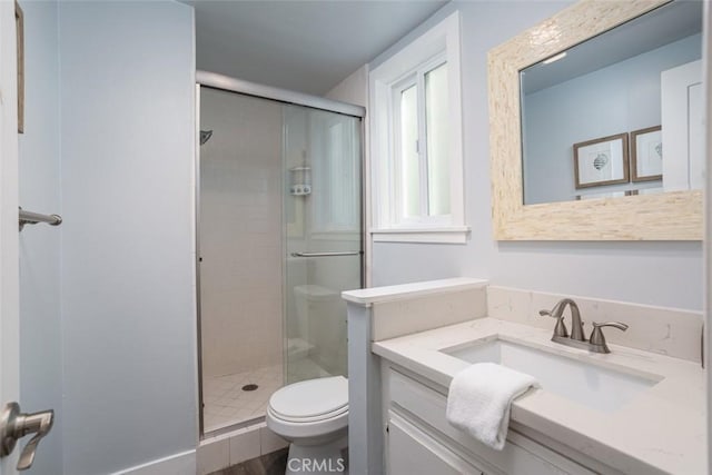 bathroom featuring vanity, toilet, and a shower with door