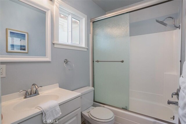 full bathroom with shower / bath combination with glass door, vanity, and toilet