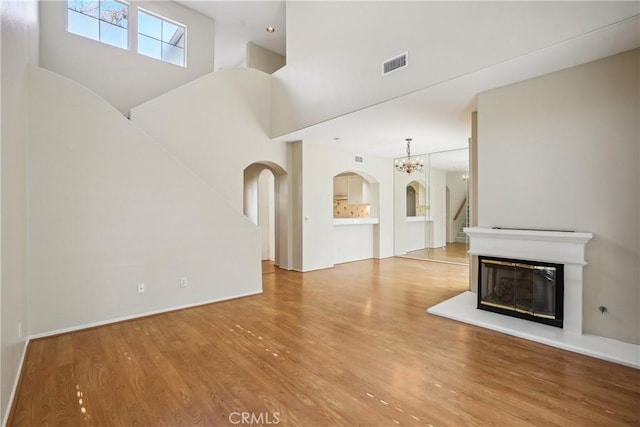 unfurnished living room featuring a chandelier, a high ceiling, and hardwood / wood-style flooring