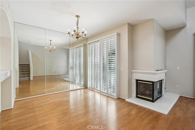 unfurnished living room with a chandelier and hardwood / wood-style floors