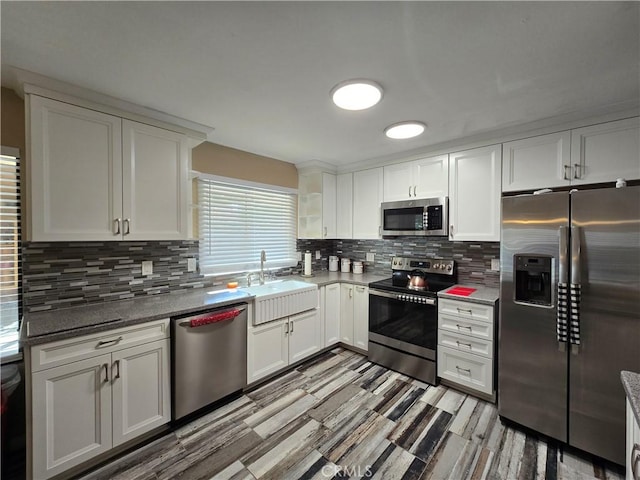 kitchen featuring white cabinets, sink, stainless steel appliances, and stone counters