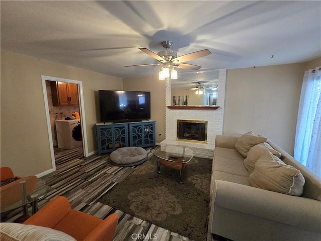 living room featuring ceiling fan, washer / dryer, and a brick fireplace