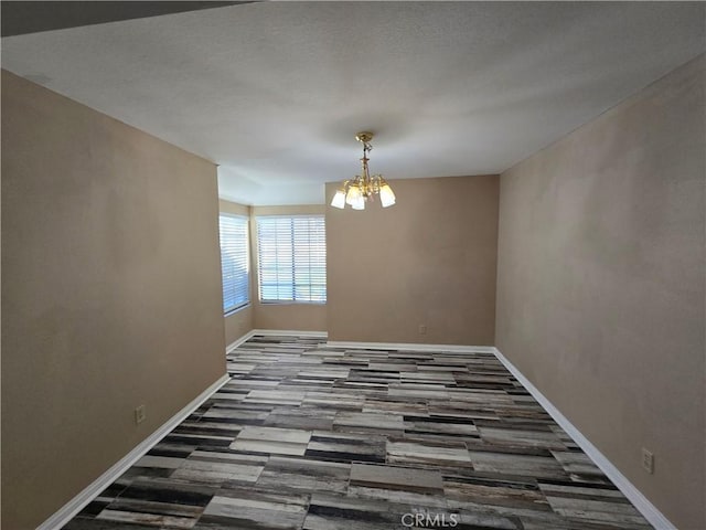 spare room with hardwood / wood-style floors and a chandelier