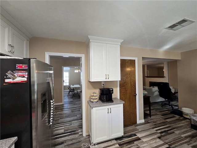 kitchen featuring white cabinets, stainless steel fridge with ice dispenser, dark hardwood / wood-style floors, and light stone counters