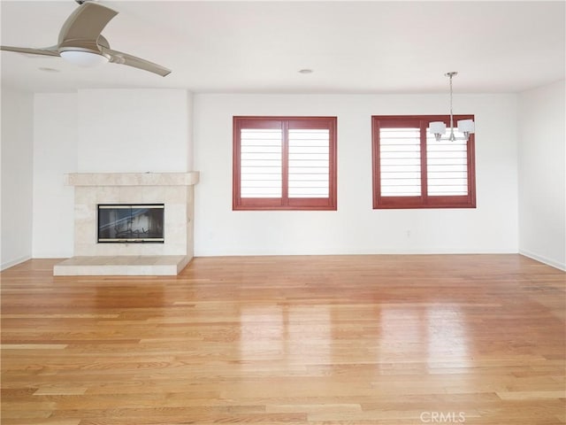 unfurnished living room featuring a tiled fireplace, ceiling fan, and light hardwood / wood-style flooring