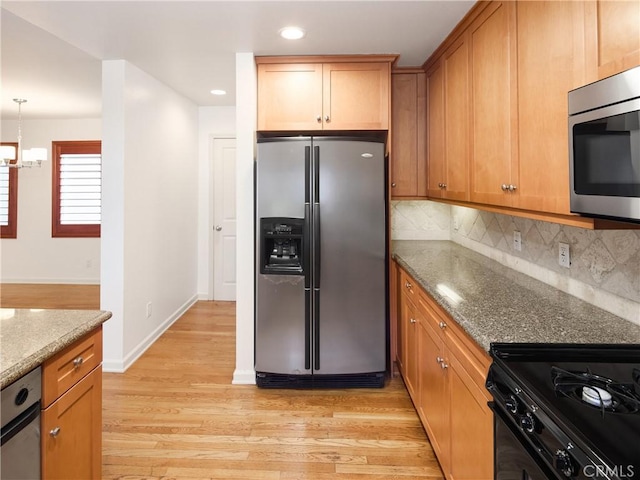 kitchen featuring stone counters, tasteful backsplash, light hardwood / wood-style floors, a chandelier, and appliances with stainless steel finishes