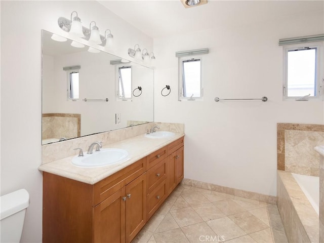 bathroom with tile patterned flooring, vanity, toilet, and tiled tub