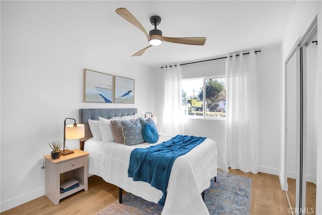 bedroom with light wood-type flooring, ceiling fan, and a closet