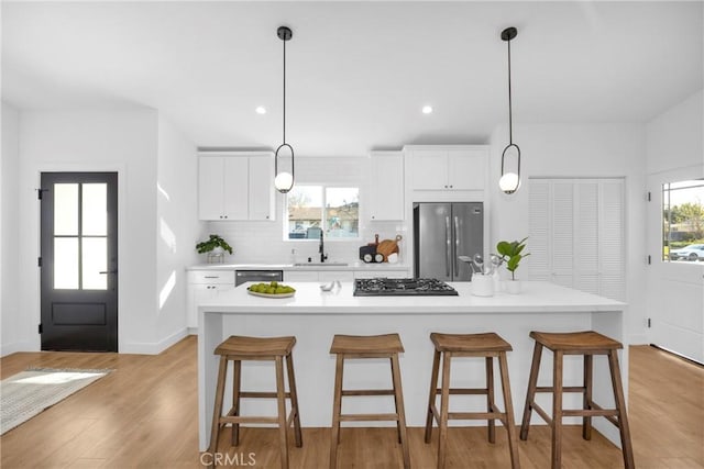 kitchen with stainless steel appliances, white cabinets, a center island, and tasteful backsplash