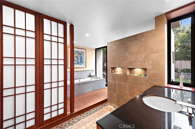 bathroom with tiled bath, tile patterned floors, and tile walls