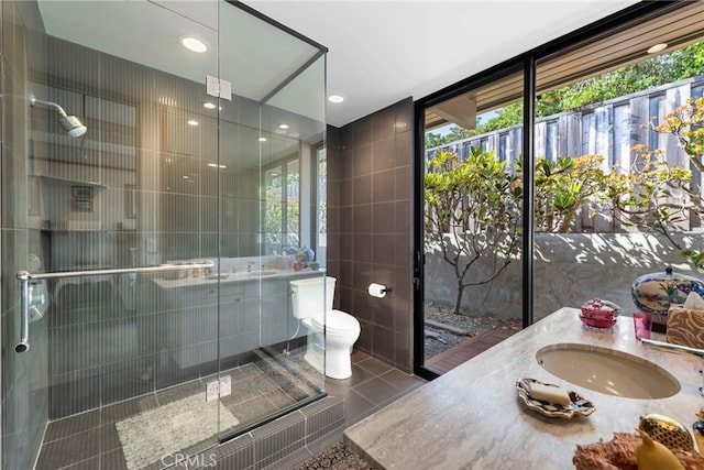 bathroom featuring vanity, tile patterned floors, toilet, tile walls, and a healthy amount of sunlight