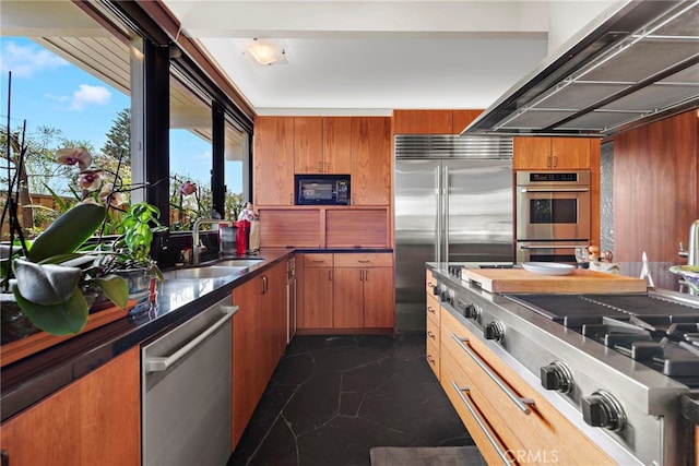 kitchen featuring built in appliances, wood walls, and sink