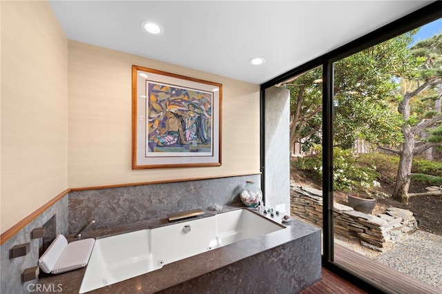 bathroom featuring a relaxing tiled tub, floor to ceiling windows, and wood-type flooring