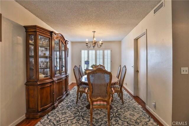 dining area with an inviting chandelier, hardwood / wood-style floors, and a textured ceiling