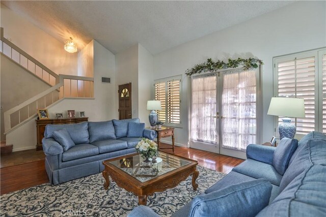 living room with vaulted ceiling, hardwood / wood-style flooring, french doors, and a wealth of natural light