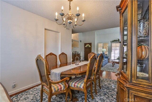 dining space with an inviting chandelier, light hardwood / wood-style floors, and a textured ceiling