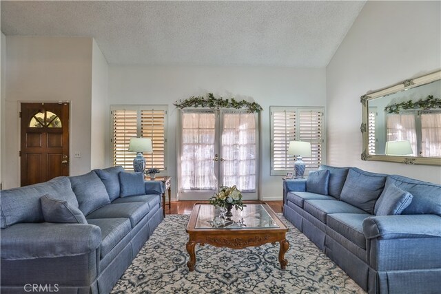 living room featuring vaulted ceiling, a textured ceiling, french doors, and wood-type flooring