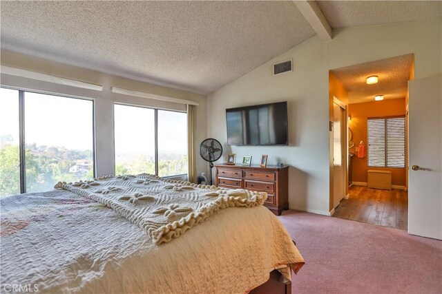 bedroom with a textured ceiling, light carpet, and vaulted ceiling with beams