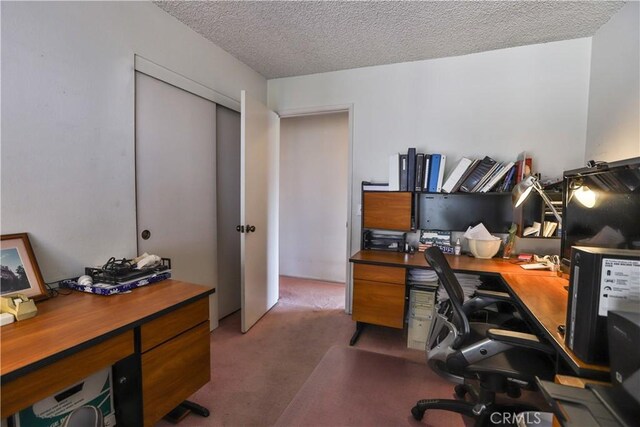 carpeted home office featuring a textured ceiling