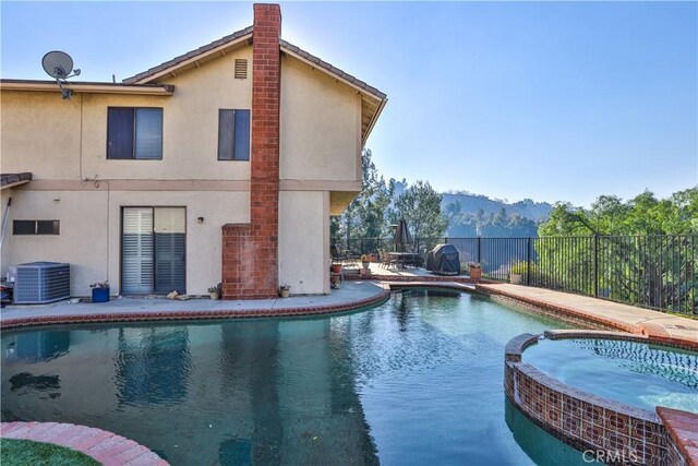 view of pool with an in ground hot tub, central AC, and a mountain view